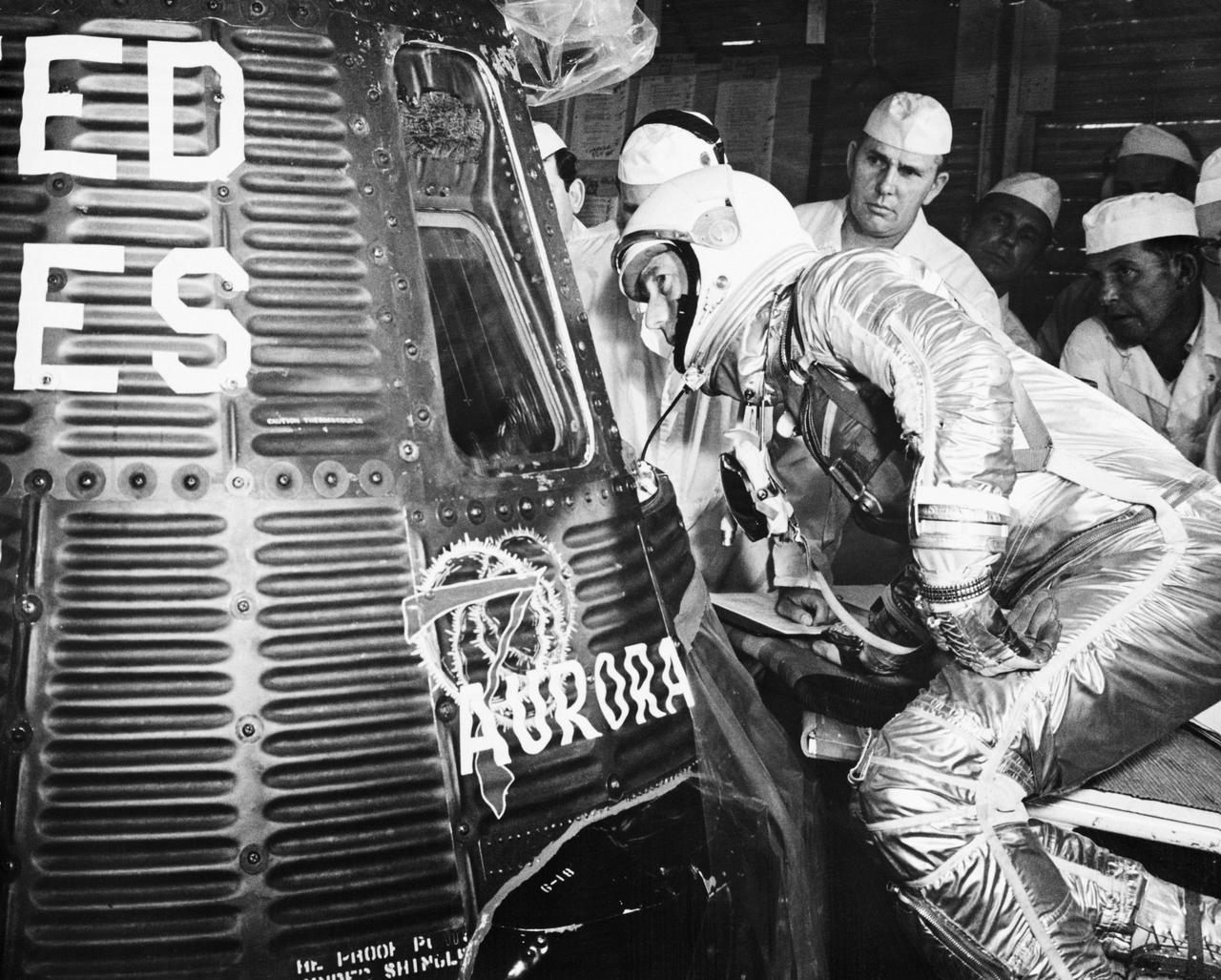 Scott Carpenter looking into the Aurora 7 Mercury spacecraft before launch